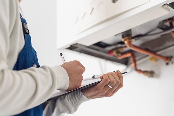 plumber with checklist checking boiler